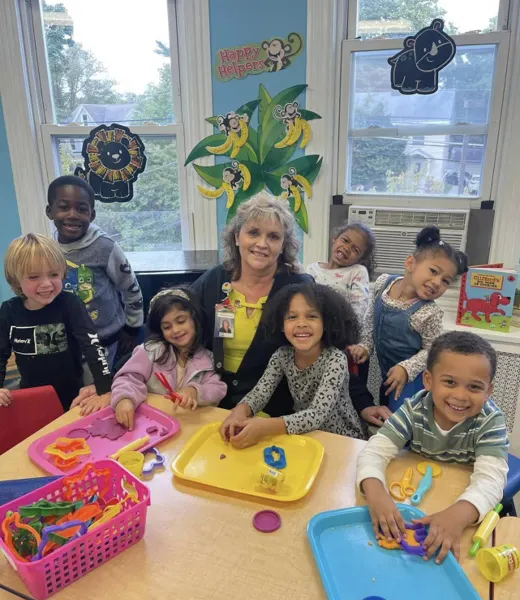 A teacher with a group of children at a classroom table