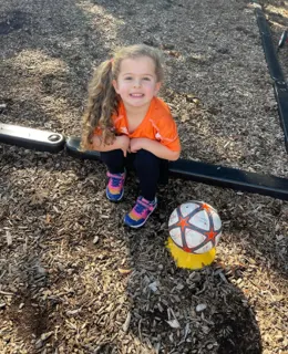 A child sitting outside with a soccer ball